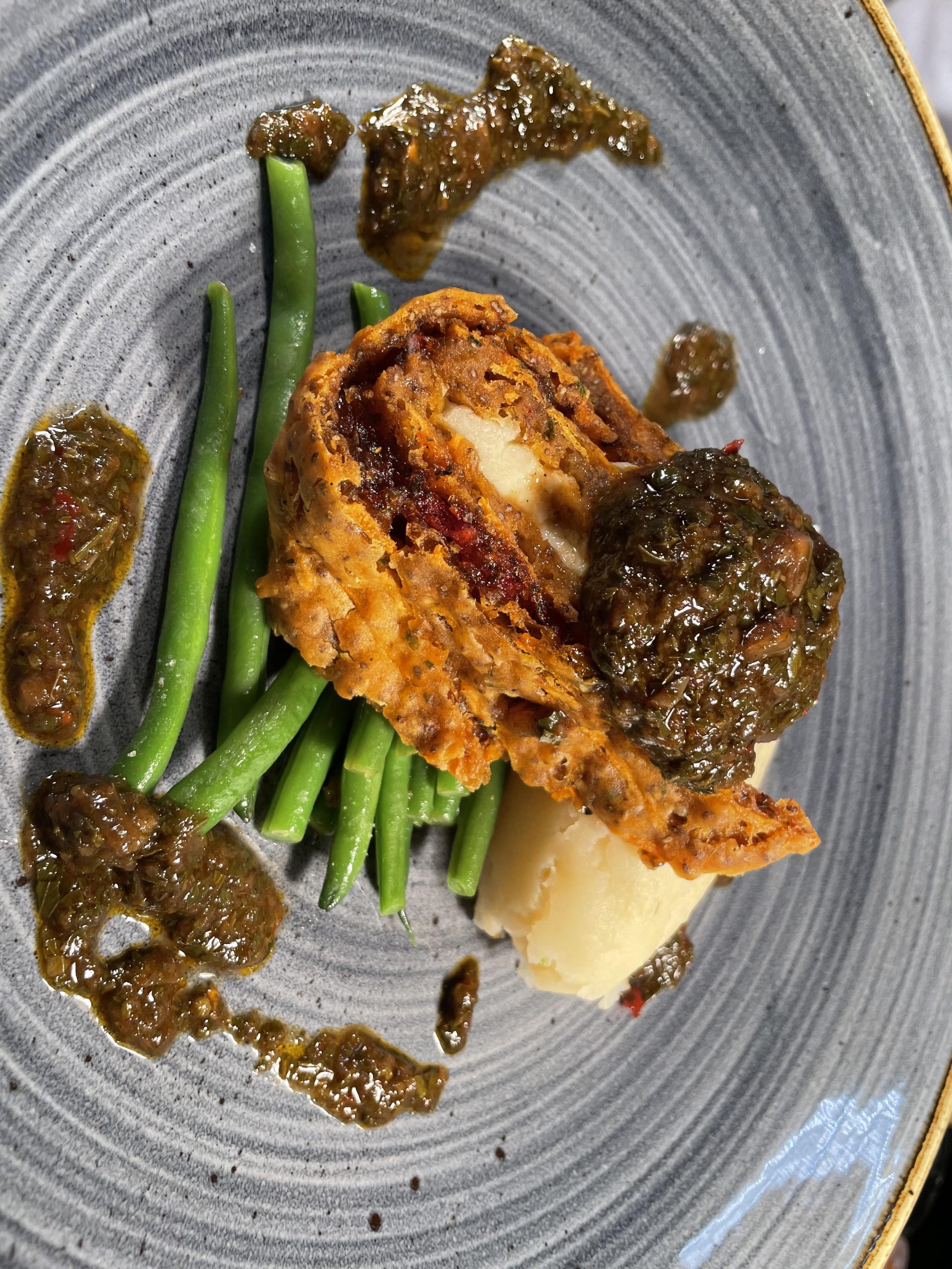 Cajun spiced sweet potato roulade with creamy mash, zesty garlic green beans and chimichurri sauce